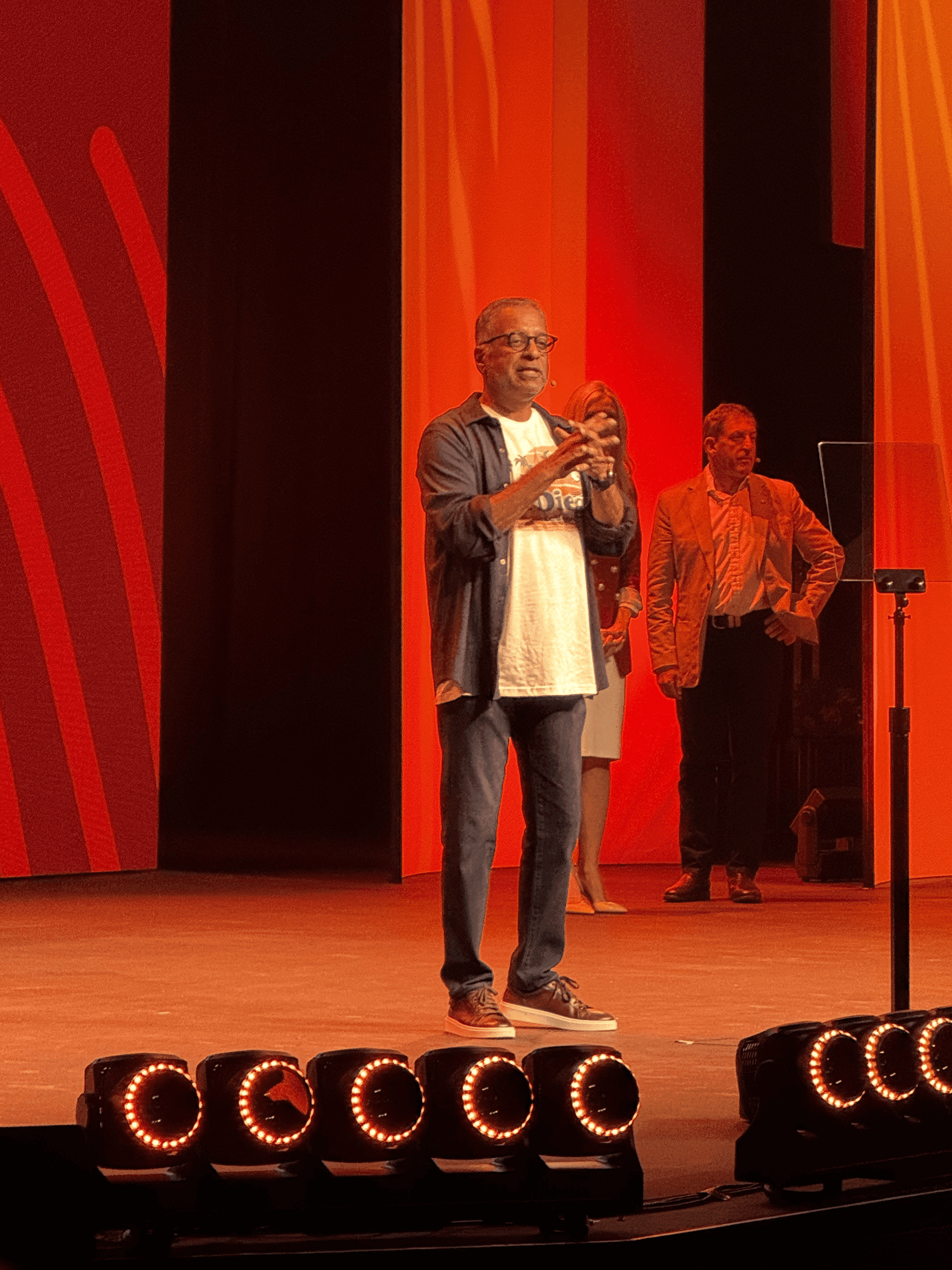 Rajeev speaking on a red-lit stage